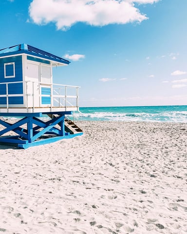 Blue and white lifeguard tower on a white sand Florida beach under clear sky